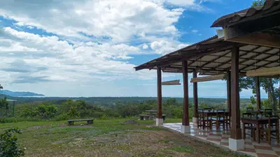 a wooden pavilion with tables and benches on a field at Tarcoles Birding Lodge in Tarcoles