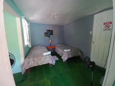 a small room with two beds and a door at Donde Familia Manito in Paquera