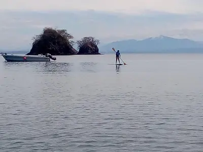 a man standing on a paddle board in the water at Donde Familia Manito in Paquera