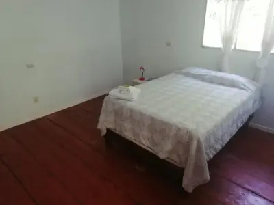 a bedroom with a bed with a table and a window at Donde Familia Manito in Paquera