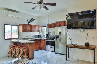 a kitchen with wooden cabinets and a stainless steel refrigerator at Casa Lapa Oceanside Villa in Playa Hermosa