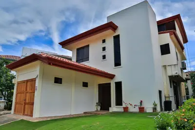 a white house with a green yard at Casa Lapa Penthouse Oceanside Villa in Playa Hermosa