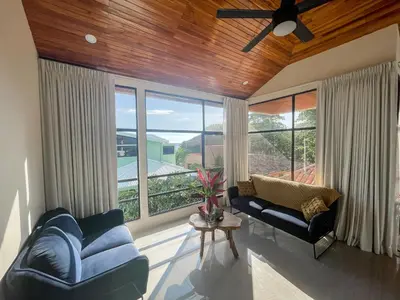 a living room with a couch and a large window at Casa Lapa Penthouse Oceanside Villa in Playa Hermosa