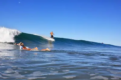 a group of people riding a wave on a surfboard in the ocean at Villa Venus in Santa Teresa Beach