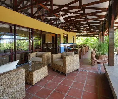 an outdoor patio with chairs and tables and windows at Unique Architecture, 3 Pools and Wi-Fi in Orotina