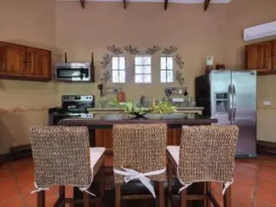 a kitchen with a counter with chairs and a refrigerator at Private Pool & WiFi in Puntarenas