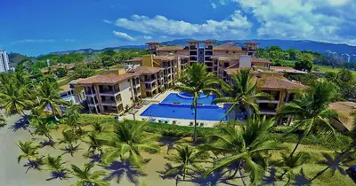 an aerial view of a resort with a pool and palm trees at BEACHFRONT Condo Bahia Encantada L1 Jaco Beach in Jacó