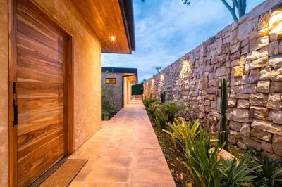 a walkway leading to a stone wall at LALOON Luxury Suites - Adults Only in Santa Teresa Beach