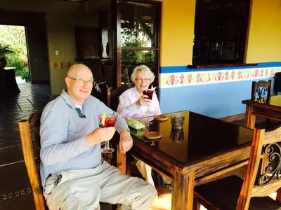 an older man and woman sitting at a table with drinks at Unique 5 Architectural Homes, Pool & Wi-Fi in Lagunillas