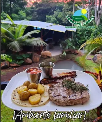 a plate of food with meat and potatoes on a table at Guapote Lodge in Tigra