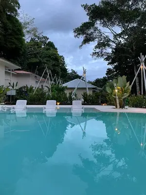 a swimming pool with three chairs and windmills at Grand Park Manuel Antonio - Adults Only in Manuel Antonio