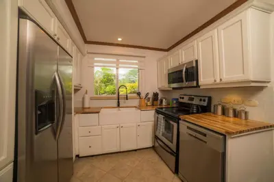 a kitchen with white cabinets and a stainless steel refrigerator at Veranda 6F 2 bdr Garden View in Los Suenos in Herradura
