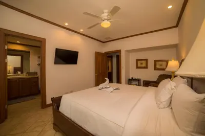 a bedroom with a white bed with a ceiling fan at Veranda 6F 2 bdr Garden View in Los Suenos in Herradura