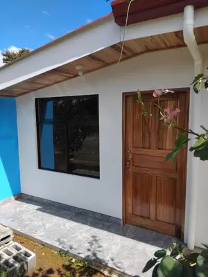 a detached house with a wooden door at Cabinas El Pilón Río Celeste in San Rafael