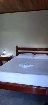 a bed with a wooden frame and white sheets and pillows at Cabinas El Pilón Río Celeste in San Rafael