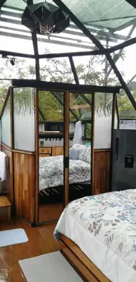a bedroom with a bed and a glass wall at Cristal House Mountain View in Heredia