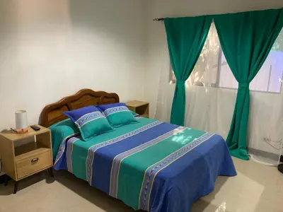 a bedroom with a bed with blue and green sheets and a window at Casa Binisa Fresca y agradable in Liberia