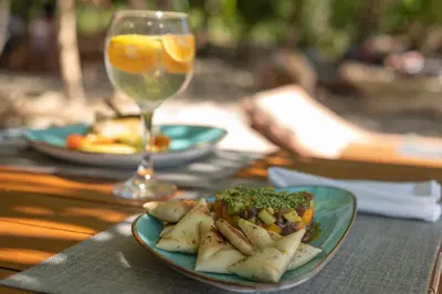 a table with a plate of food and a glass of wine at Los Vivos Beachfront Experience in Pochote