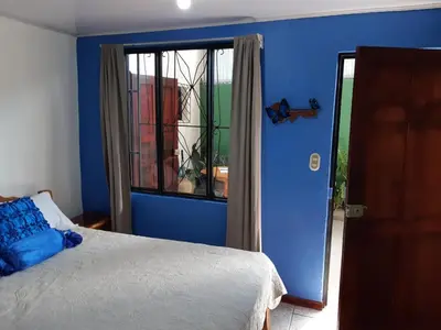 a bedroom with blue walls and a bed and a window at Cabinas Chazu #2 in Quepos