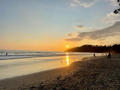 a group of people walking on the beach at sunset at Cabinas Chazu #2 in Quepos