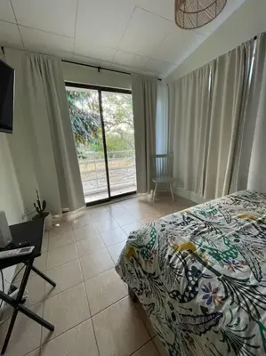 a bedroom with a bed and a desk and a window at Casa Buda 2 Liberia cerca del aeropuerto in Liberia
