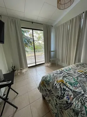 a bedroom with a bed and a desk and a window at Casa Buda 2 Liberia cerca del aeropuerto in Liberia