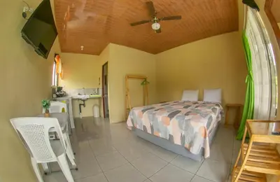 a bedroom with a bed and a table and a kitchen at Chongos Place in Fortuna
