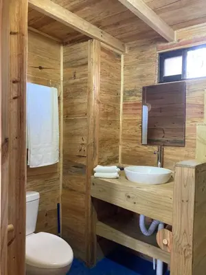 a wooden bathroom with a toilet and a sink at Bungalows Baobab in San Isidro