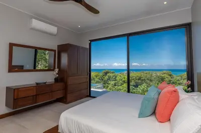 a bedroom with a bed and a large window at Casa Solaz - by Pura Villas in Dominical
