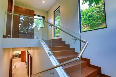 a staircase in a house with a glass railing at Casa Solaz - by Pura Villas in Dominical