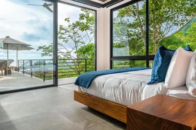 a bedroom with a bed and a view of the ocean at Casa Amigos - By Pura Villas in Dominical