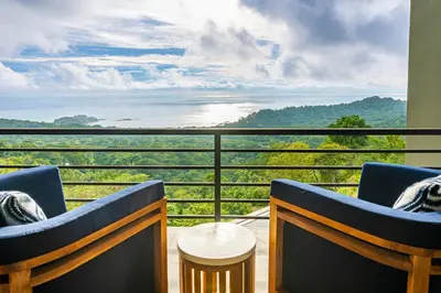 a balcony with two chairs and a view of the ocean at Casa Amigos - By Pura Villas in Dominical