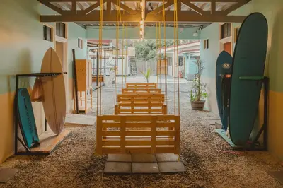 a row of wooden benches with surfboards in a room at Habitat Surf Glamp in Santa Teresa Beach