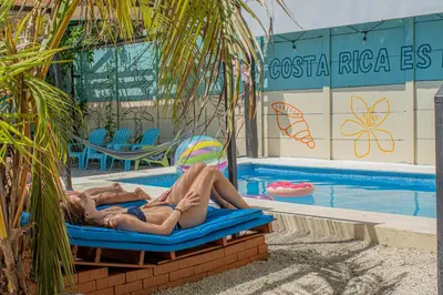 a man laying on a raft in front of a swimming pool at Habitat Surf Glamp in Santa Teresa Beach