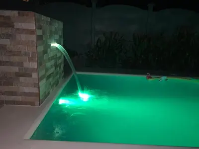 a swimming pool with a green light in the dark at Cabaña ValFio Bahía Ballena in Uvita
