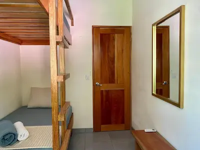 a room with a bunk bed and a wooden door at El Hostel del Patio in Tortuguero