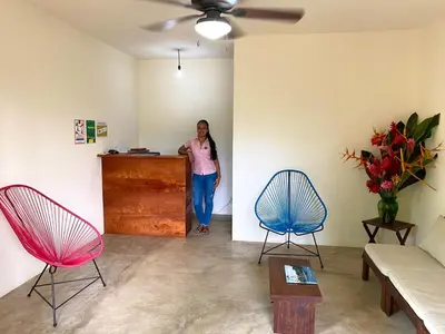 a woman standing in a room with two chairs at El Hostel del Patio in Tortuguero