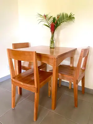 a wooden table and chairs with a vase with a plant at El Hostel del Patio in Tortuguero