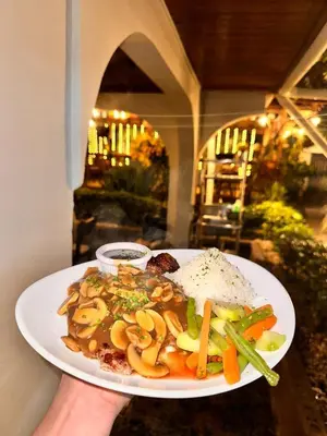a person holding a plate of food on a table at Brillasol Airport Hotel in Alajuela City