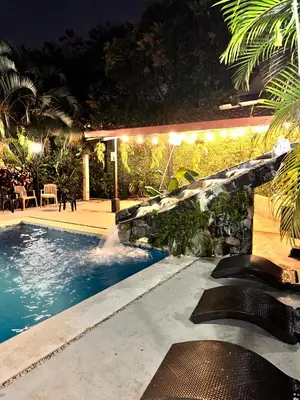 a swimming pool in a backyard at night at Brillasol Airport Hotel in Alajuela City