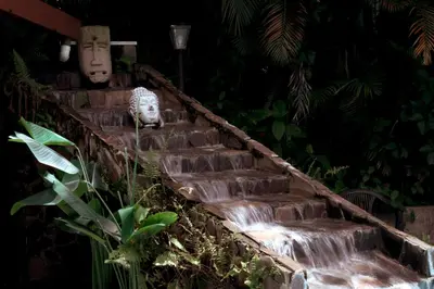 a set of stairs with a waterfall in a garden at Brillasol Airport Hotel in Alajuela City