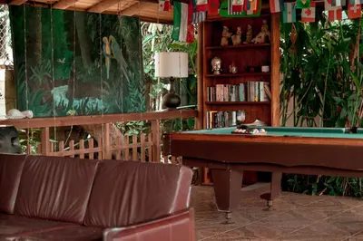 a living room with a pool table and a book shelf at Brillasol Airport Hotel in Alajuela City