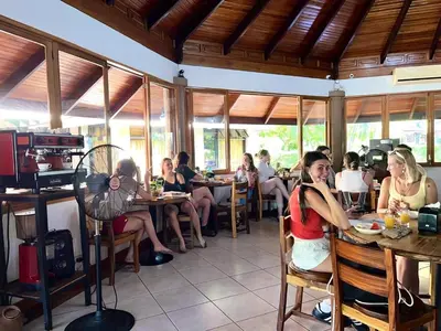 a group of people sitting at tables in a restaurant at Hotel Villa Acacia in Playa Hermosa