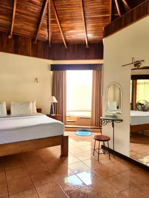 a bedroom with a bed and a large window at Hotel Villa Acacia in Playa Hermosa