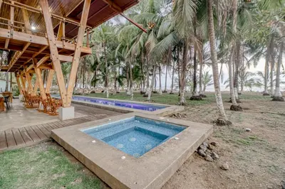 a swimming pool in front of a resort with palm trees at Mangue House in Playa San Miguel