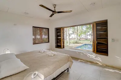 a bedroom with a bed with a ceiling fan and a window at Mangue House in Playa San Miguel