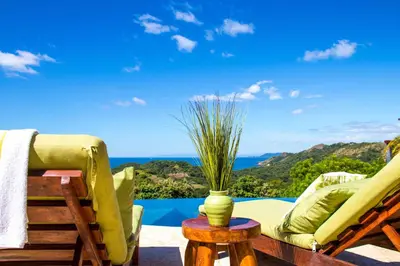 a patio with chairs and a vase on a table at Luxury Home with Views and Infinity Pool Near Beach! in Puerto Viejo