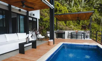 a patio with a white couch and a swimming pool at Le Suite in Santa Teresa Beach