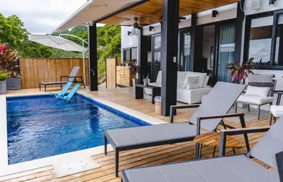 a house with a swimming pool with chairs and a patio at Le Suite in Santa Teresa Beach