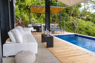 a pool with white furniture next to a swimming pool at Le Suite in Santa Teresa Beach